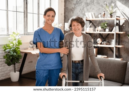 Portrait pf happy smiling caretaker medicine worker nurse helping elderly senior old patient with walking frame. Rehabilitation after trauma injury Royalty-Free Stock Photo #2395115157