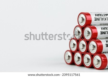stack of used red alkaline AA batteries lying in pyramid form, disposal of chemical current sources concept, isolated on white background, copy space