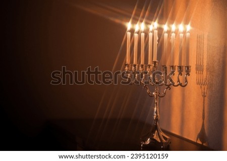 Hanukkah menorah, or hanukkiah in the light of the sun at sunset for Jewish holiday Hanukkah. Hanukkah lamp, nine-branched candelabrum with burning candles with star filter. Royalty-Free Stock Photo #2395120159
