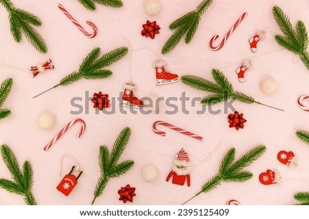 Different types of decorations from fir branches, Christmas tree toys and candies lie chaotically on a pink textured background, flat lay close-up.