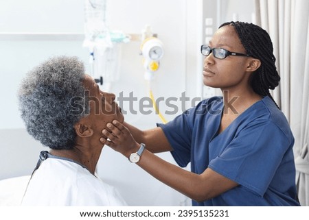 African american female doctor testing eyes of senior female patient in hospital room. Medicine, healthcare and medical services, unaltered. Royalty-Free Stock Photo #2395135231