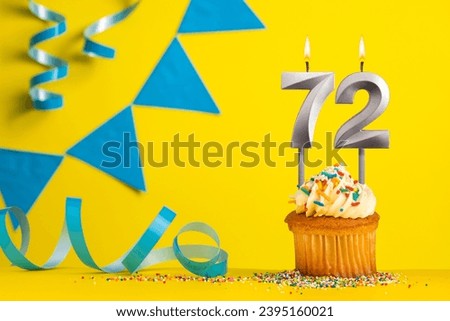 Birthday candle number 72 with cupcake - Yellow background with blue pennants Royalty-Free Stock Photo #2395160021