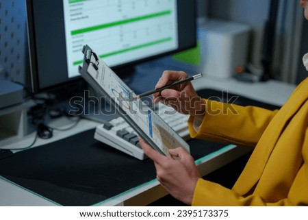 Businesswoman working in pile of paper files to find and check unfinished documents on folder documents and check Compare data on the PC on the office desk.