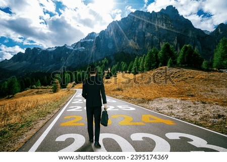 2024 New Year journey and future vision concept . Businessman traveling on highway road leading forward to happy new year celebration in beginning of 2024 for bliss and successful start . Royalty-Free Stock Photo #2395174369