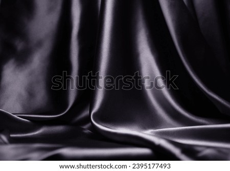 The backdrop is a gray-black satin fabric, a dark, shiny fabric, an abstract silk with a beautiful blurred light wave pattern.