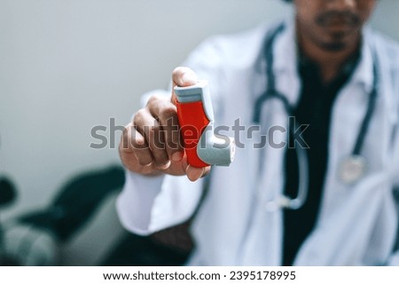 Male doctor holding and showing asthma inhaler. Medical portable equipment for asthma attack.  Royalty-Free Stock Photo #2395178995