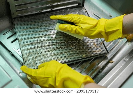 Housekeeping put stained filters of cooker hood in sink before cleaning it by sponge. Clean your filters every two to three months, depending on your cooking habits. Royalty-Free Stock Photo #2395199319