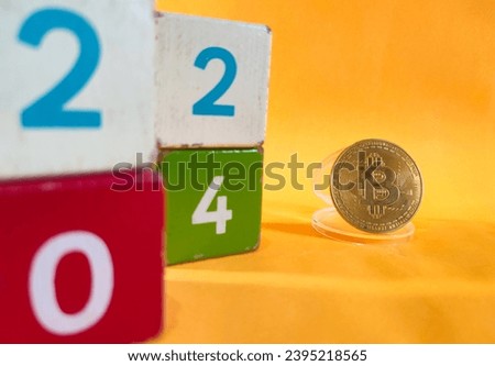Colored wooden blocks and bitcoin on orange background, new year concept and bitcoin price in 2024, SHOTLISTbanking
