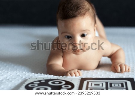 A baby looks at a black and white contrast educational book. Intellectual development of newborns. Developing cards for children.