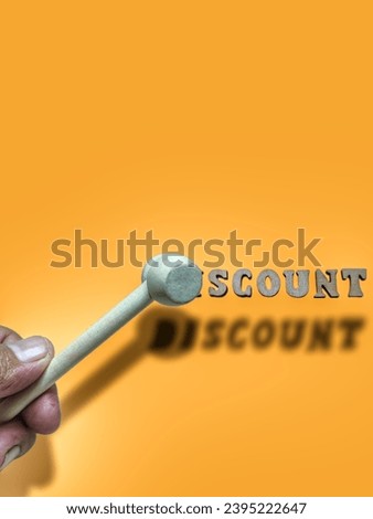 focus on the small gray hammer on the finger and the arrangement of the brown alphabet. there is a black shadow behind the picture. the background is brown
