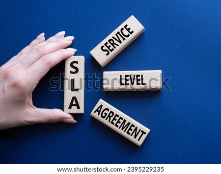 SLA - Service Level Agreement. Wooden blocks with word SLA. Businessman hand. Beautiful deep blue background. Business and Service Level Agreement concept. Copy space.