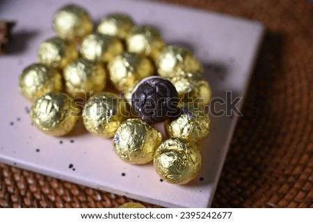 Round chocolate candies in a golden wrapper. Round candies. Golden color. A holiday gift. Birthday. Food photo. Sweet food. Happy birthday. Background image. Chocolate.