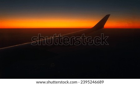 View from the airplane window at a beautiful sunset  and the airplane wing. Red sky as seen through window of an airplane.