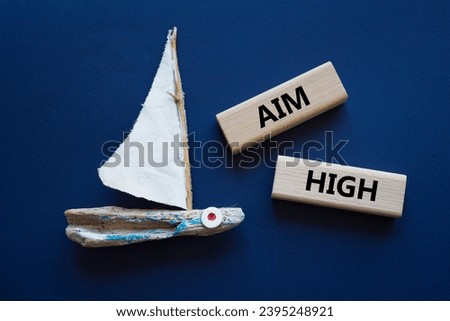 Aim High symbol. Wooden blocks with words Aim High. Beautiful deep blue background with boat. Business and Aim High concept. Copy space.