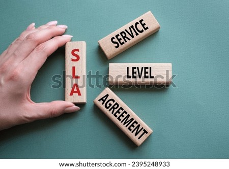 SLA - Service Level Agreement. Wooden blocks with word SLA. Businessman hand. Beautiful grey green background. Business and Service Level Agreement concept. Copy space.