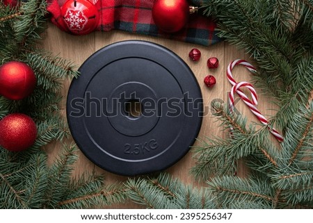 Dumbbell barbell weight plate, Christmas bauble ornaments decorations and fir tree branches. Healthy fitness lifestyle winter holiday season composition. Gym workout, sport training flat lay concept.