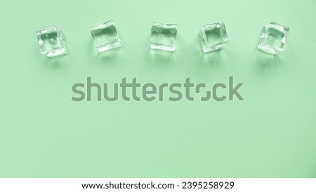 Concept of cold and refreshing. Ice cubes with water drops on a green background.