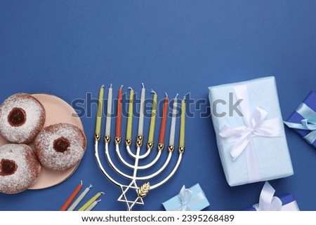 Flat lay composition with Hanukkah menorah and donuts on blue background, space for text