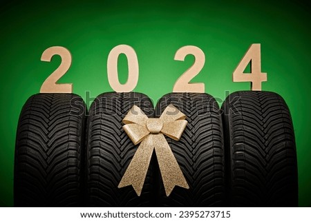 Car tires, new tyres, winter wheels isolated on green background with bow ribbon present 2024 new year celebration.