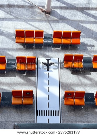 The sign of a plane on the floor and empty orange seats in the airport