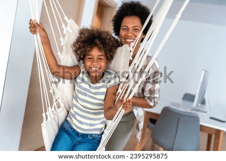 Portrait of happy black woman and her cute preteen daughter having fun together at home