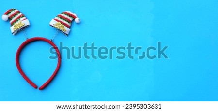 Beautiful headband 
 Decorative red Santa Hat isolate on a blue backdrop.
concept of joyful Christmas party,New year is coming soon, festive season decoration with Christmas elements