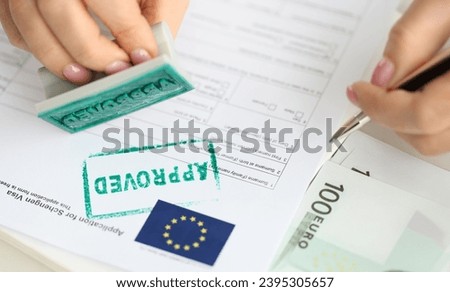 Approval of visa for travel to European Union, an employee of embassy puts stamp. Getting Schengen visa concept Royalty-Free Stock Photo #2395305657