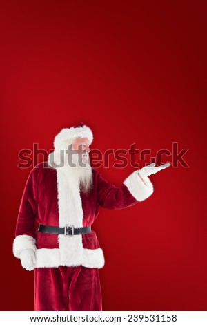 Santa shows something to camera against red background