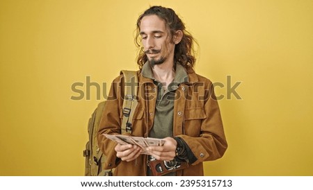 Young hispanic man tourist wearing backpack counting dollars over isolated yellow background