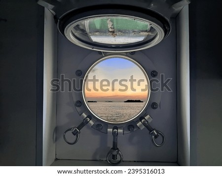 The view from the porthole window shows the beauty of the sea and sky in the morning at sunrise. Photo taken from the ship's cabin.