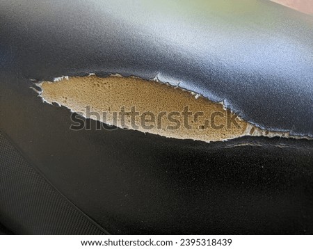 Torn black motorcycle seat due to a sharp object. Royalty-Free Stock Photo #2395318439