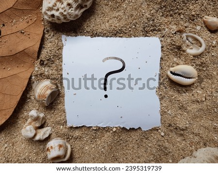 Question mark writing on beach sand background.
