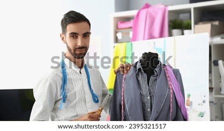 Male stylist designer holding scissors next to mannequin. Creation and tailoring of new fashion collection of clothes concept