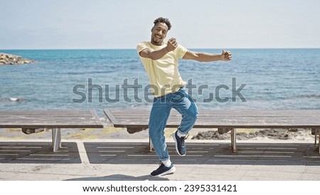 African american man smiling confident dancing at seaside