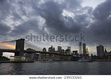Brooklyn Bridge and New York skyline across the East River at twilight on a cloudy day.