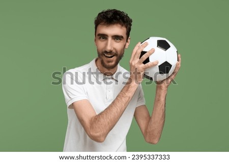 Handsome man with soccer ball on green background