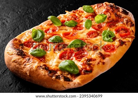 flatbread Pizza with Mozzarella cheese, Tomatoes, pepper, Spices and Fresh Basil. Italian pizza. Pizza Margherita or Margarita on Dark grey black slate background