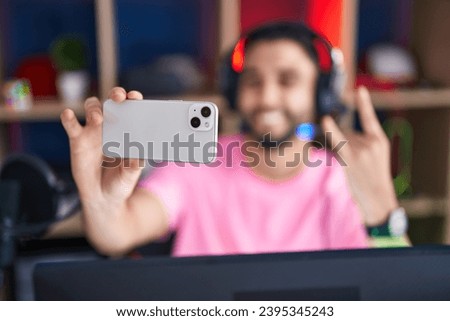 Young arab man streamer smiling confident make selfie by smartphone at gaming room