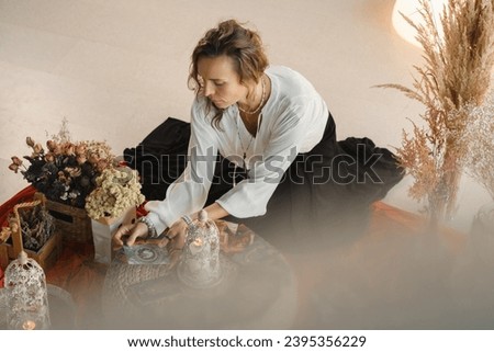 Women's circle and practice in the use of metaphorical cards. The girl is sitting surrounded by flowers. Royalty-Free Stock Photo #2395356229