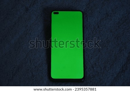 Smartphone mockup image with blank green screen on furry gray cloth background.