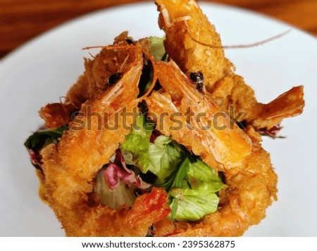 Breaded crispy deep-fried shrimps served with salad. Isolated on a white background. Close-up. Macro. Interior. Gourmet meal.