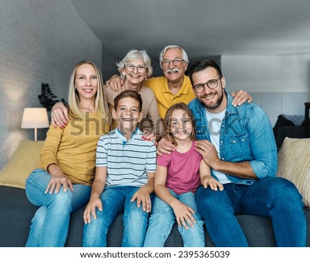 Portrait of a three generation famili, grandparents, parents and children sitting on sofa and having fun posing at home Royalty-Free Stock Photo #2395365039