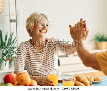 Portrait of an elderly senior couple having breakfast at home. Happy healthy affectionate senior couple eating and sitting at kitchen table having fun enjoying morning meal together Royalty-Free Stock Photo #2395365405