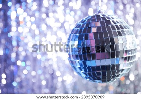 Disco ball with festive silver ribbons on background