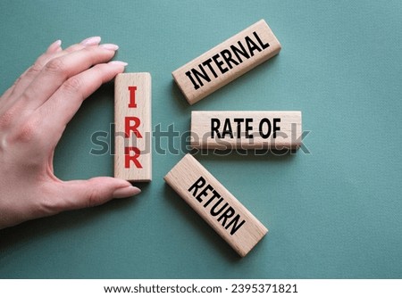 IRR - Internal Rate of Return symbol. Concept word IRR on wooden cubes. Businessman hand. Beautiful grey green background. Business and IRR concept. Copy space.