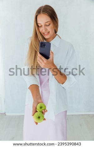 Beautiful woman taking pictures of apples in hand on her phone