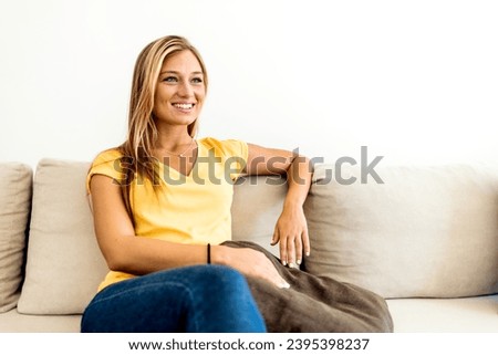 Portrait of a smiling young woman relaxing on the sofa at home. Cropped shot of attractive young woman wearing casual clothes while resting on sofa at home.