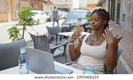 African american woman using laptop sweating at coffee shop terrace Royalty-Free Stock Photo #2395406225