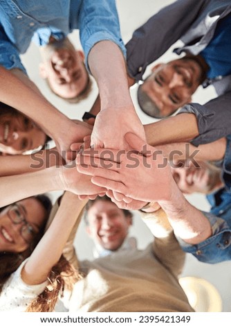 Getting it done through teamwork. Low angle shot of a group of co-workers stacking their hands on top of each other.