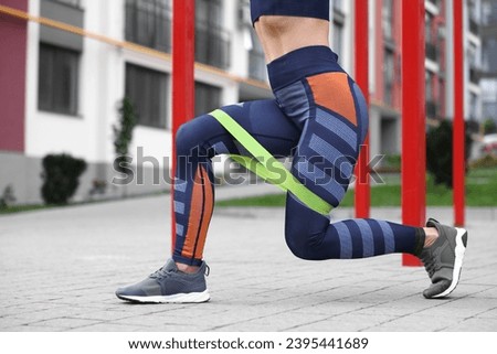 Woman doing exercise with fitness elastic band outdoors, closeup